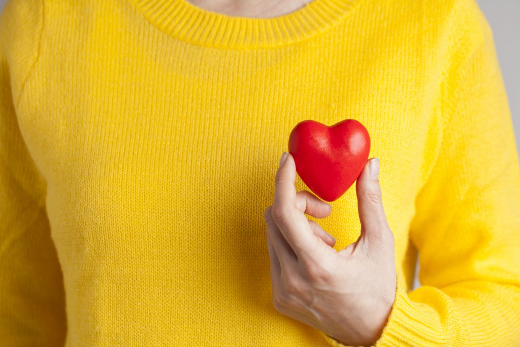 Young woman holding red heart, health insurance, donation, love concept