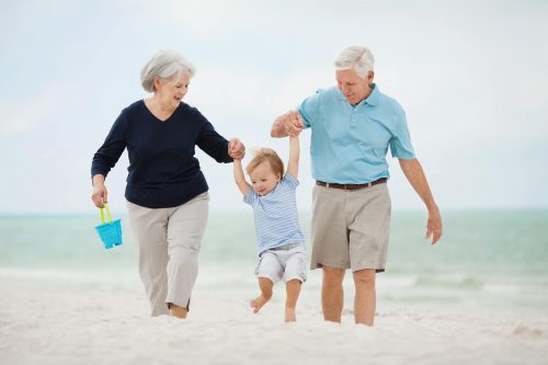 Grandparents Swinging Little Boy At Beach